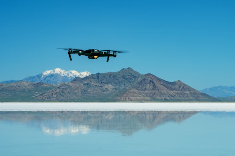 Black Drone Flying Above Body Of Water