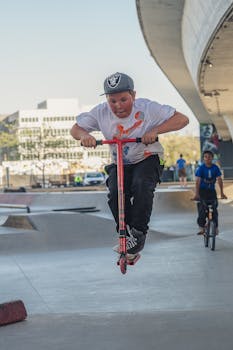 一名小男孩在滑板公园里骑着滑板车跃向半空，充满活力与趣味
