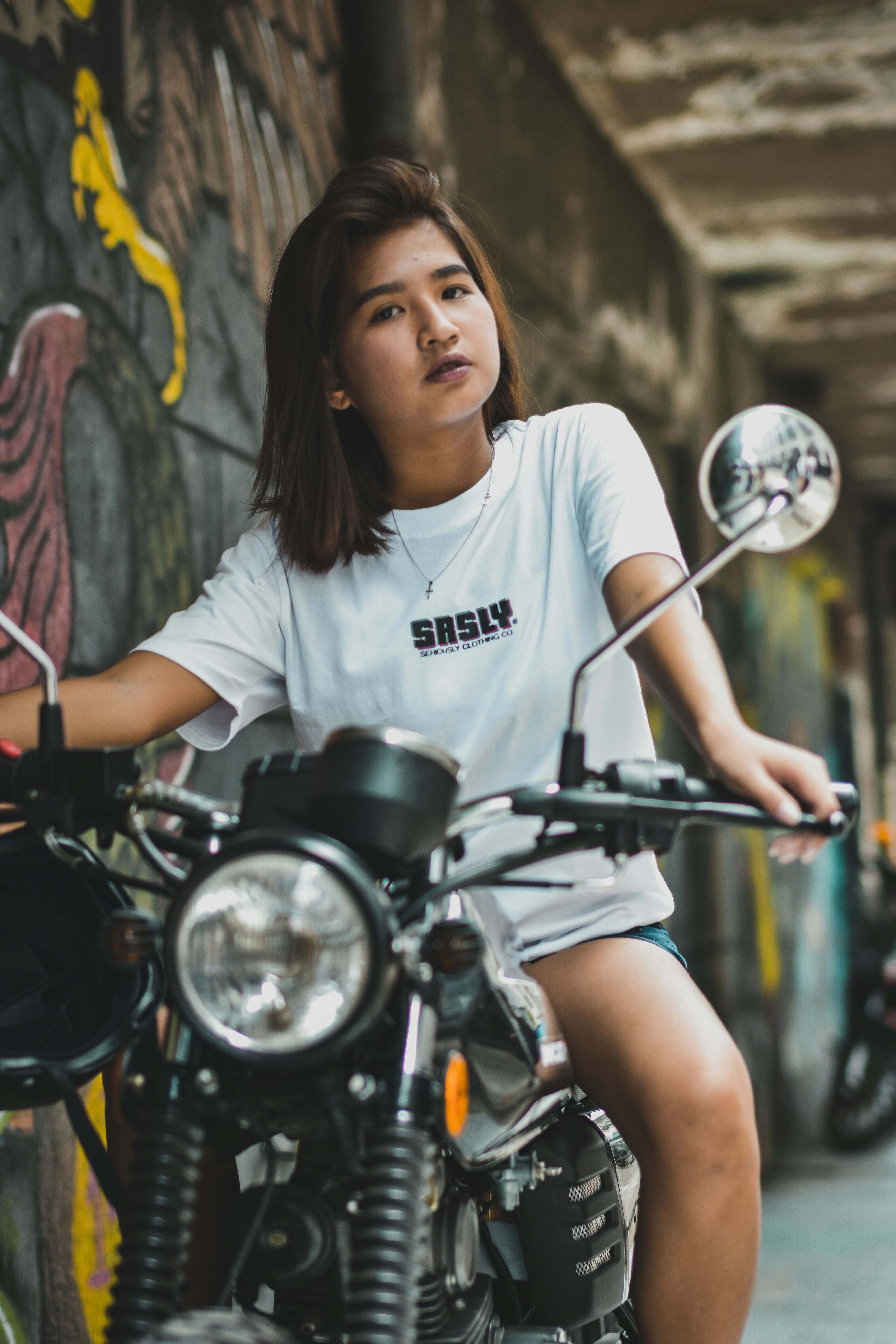 woman riding on motorcycle beside graffiti wall