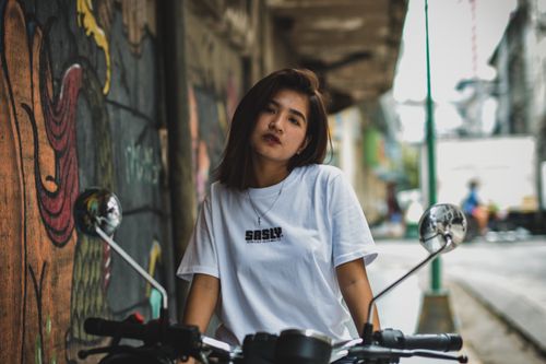 Free Trendy woman in urban setting poses with motorcycle, showcasing street style. Stock Photo