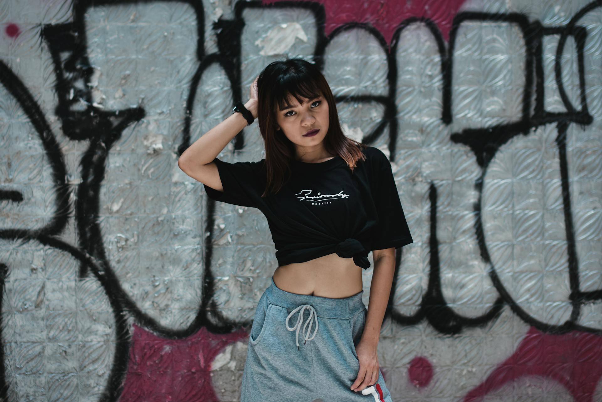 Stylish young woman posing in streetwear against graffiti wall. Urban vibe.