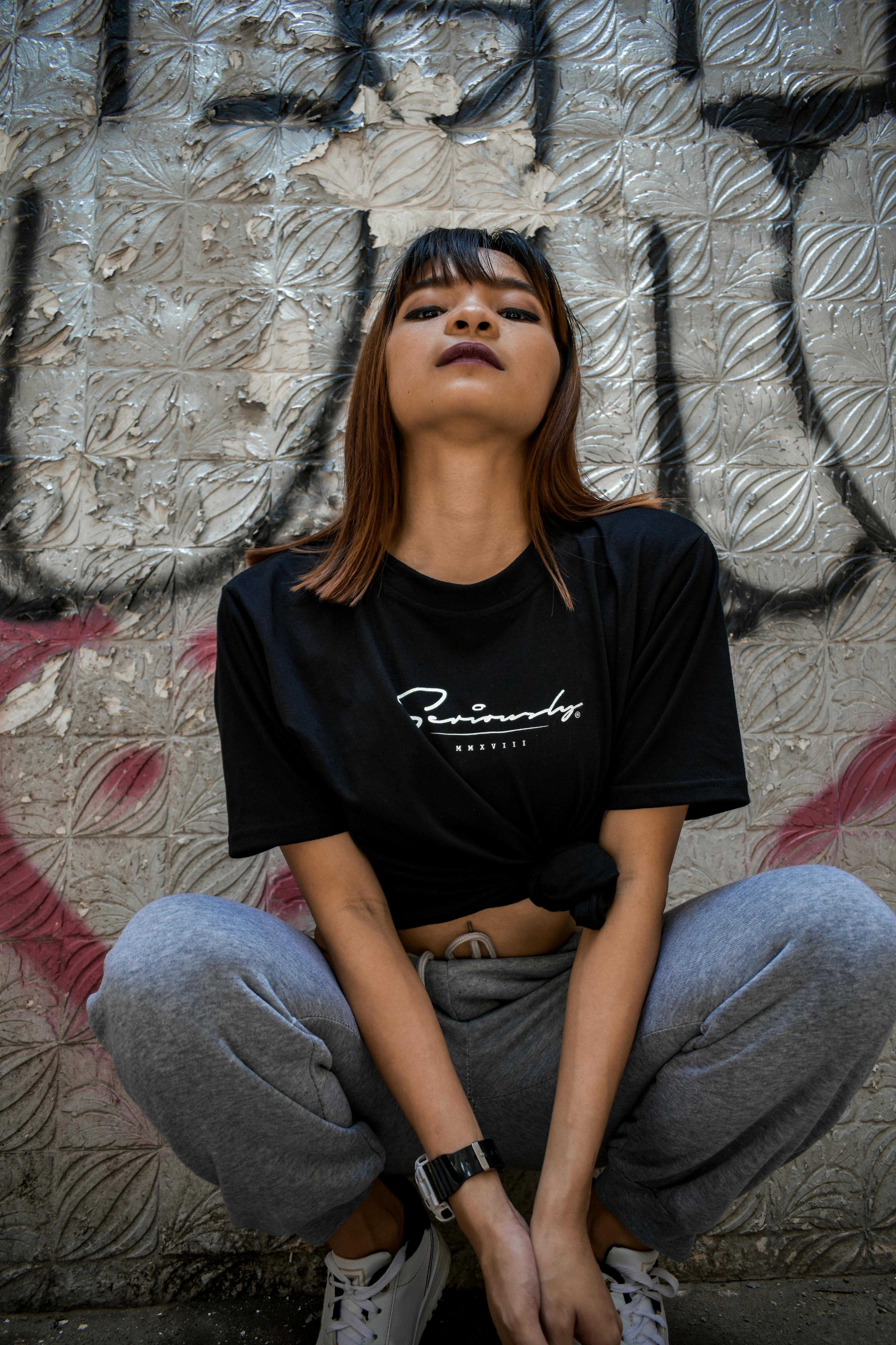 Woman Squatting Beside Graffiti Wall