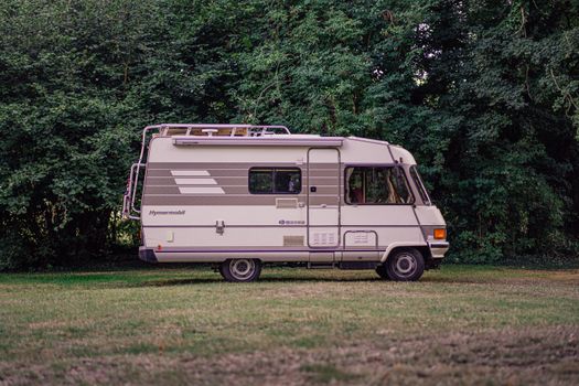 A classic Hymermobil RV parked amidst green trees and grass, perfect for exploring the outdoors.