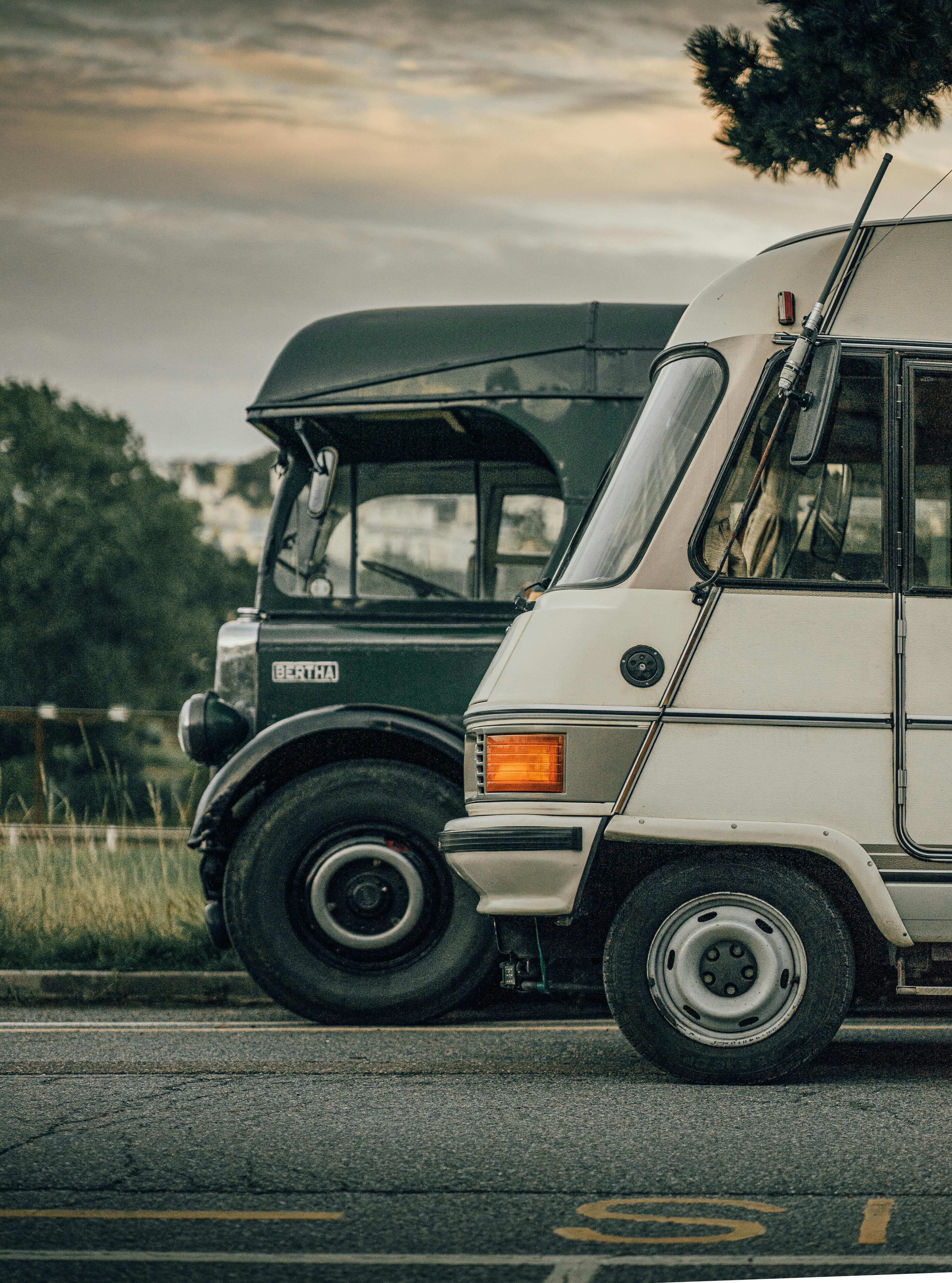 Close-up of vintage campervans parked on a road in Torquay, UK during sunset.