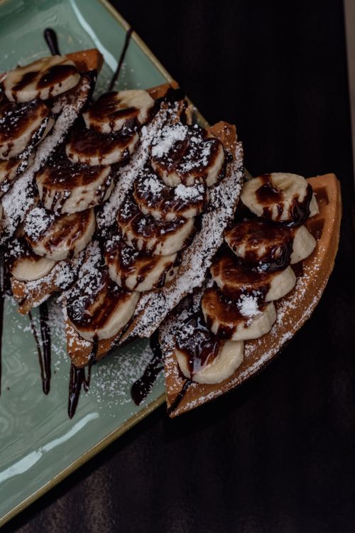 Free Indulge in sweet waffles topped with bananas, chocolate syrup, and powdered sugar. Stock Photo