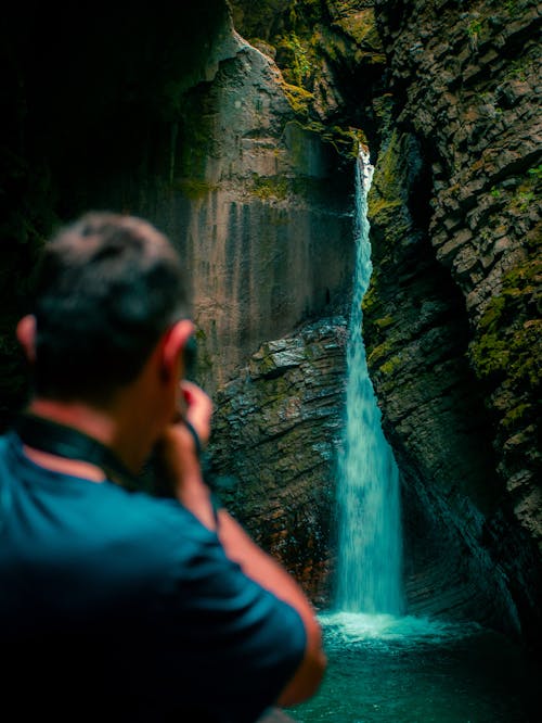 A Photographer taking a picture of a waterfall in a cave
