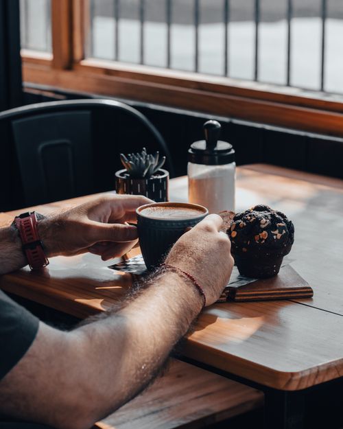 Free Man enjoying coffee and muffin in a Chillán café, sunlit table beside a window. Stock Photo