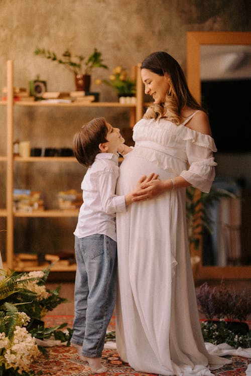 A pregnant woman and her son are standing in a room