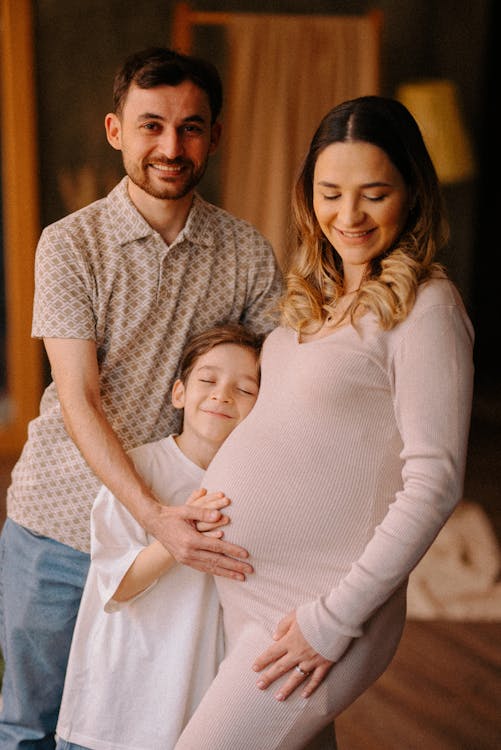 Pregnant Woman Standing with Her Husband and Son and Smiling 