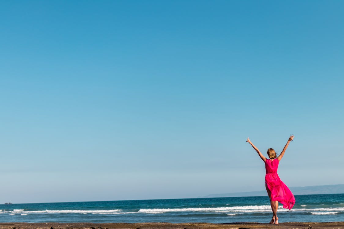 Woman Wearing Pink Dress Standing on Shore