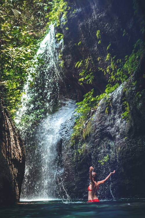 Free Woman Wearing Red Bikini Under Waterfalls Stock Photo