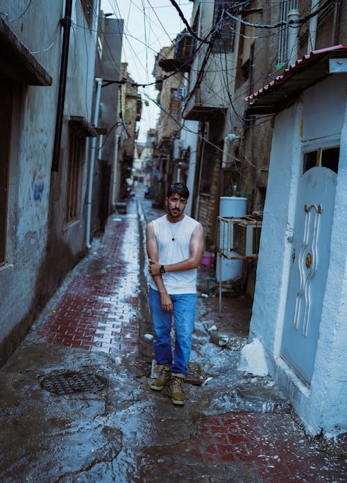 A man standing in a narrow alleyway with a baseball bat