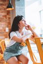 一位穿着休闲牛仔服装的女人，在灯光温暖、放着黄色椅子的舒适咖啡馆里放松