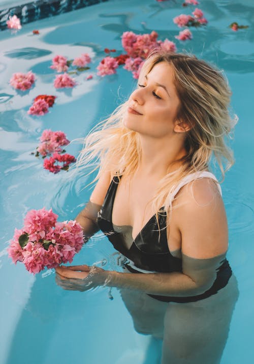 Free Woman Holding Pink Flowers In Swimming Pool Stock Photo