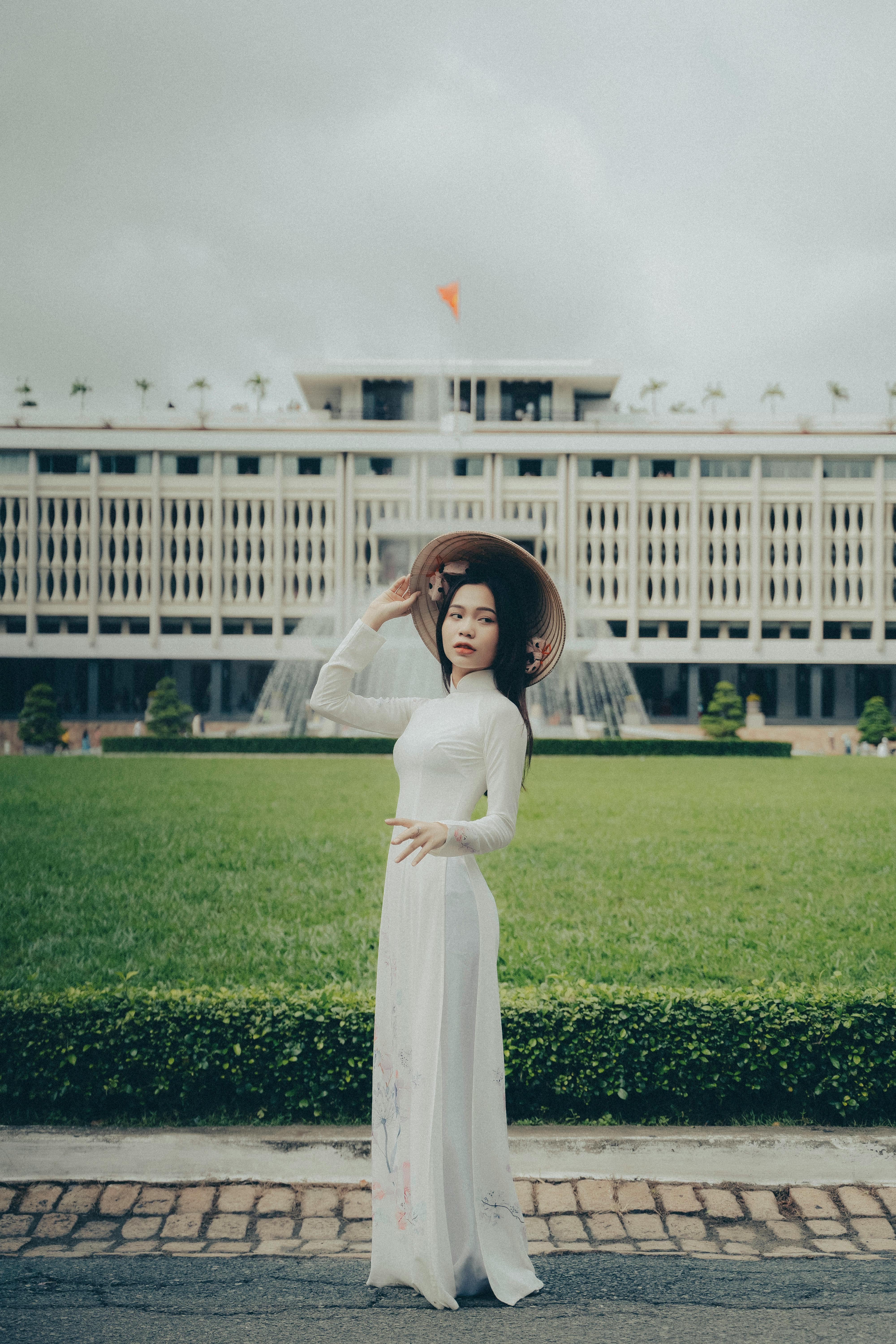 Vietnamese woman in traditional ao dai posing near Ho Chi Minh City's Independence Palace.