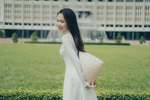 A woman in a white dress holding a bag