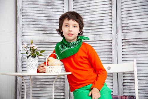 Free Boy In Red Long Sleeve Shirt Sitting Beside White Table Stock Photo