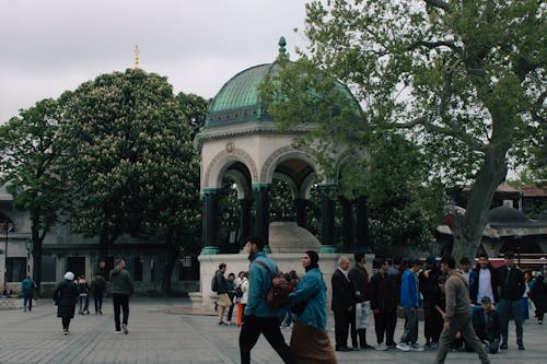 People walking around a plaza with a fountain in the middle