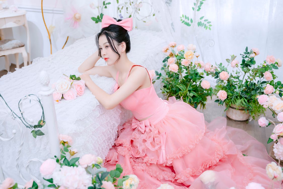 A woman in a pink dress sitting on a bed