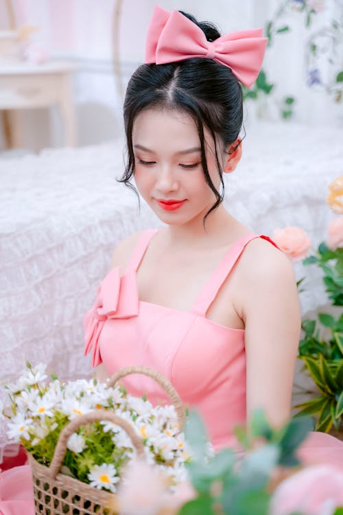 A woman in a pink dress holding a basket of flowers