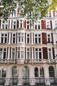 Victorian building facade with intricate details under shaded trees.