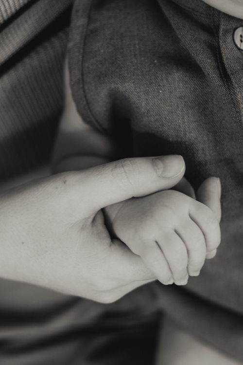Free A tender black and white close-up of a mother holding her newborn's hand, symbolizing love and connection. Stock Photo