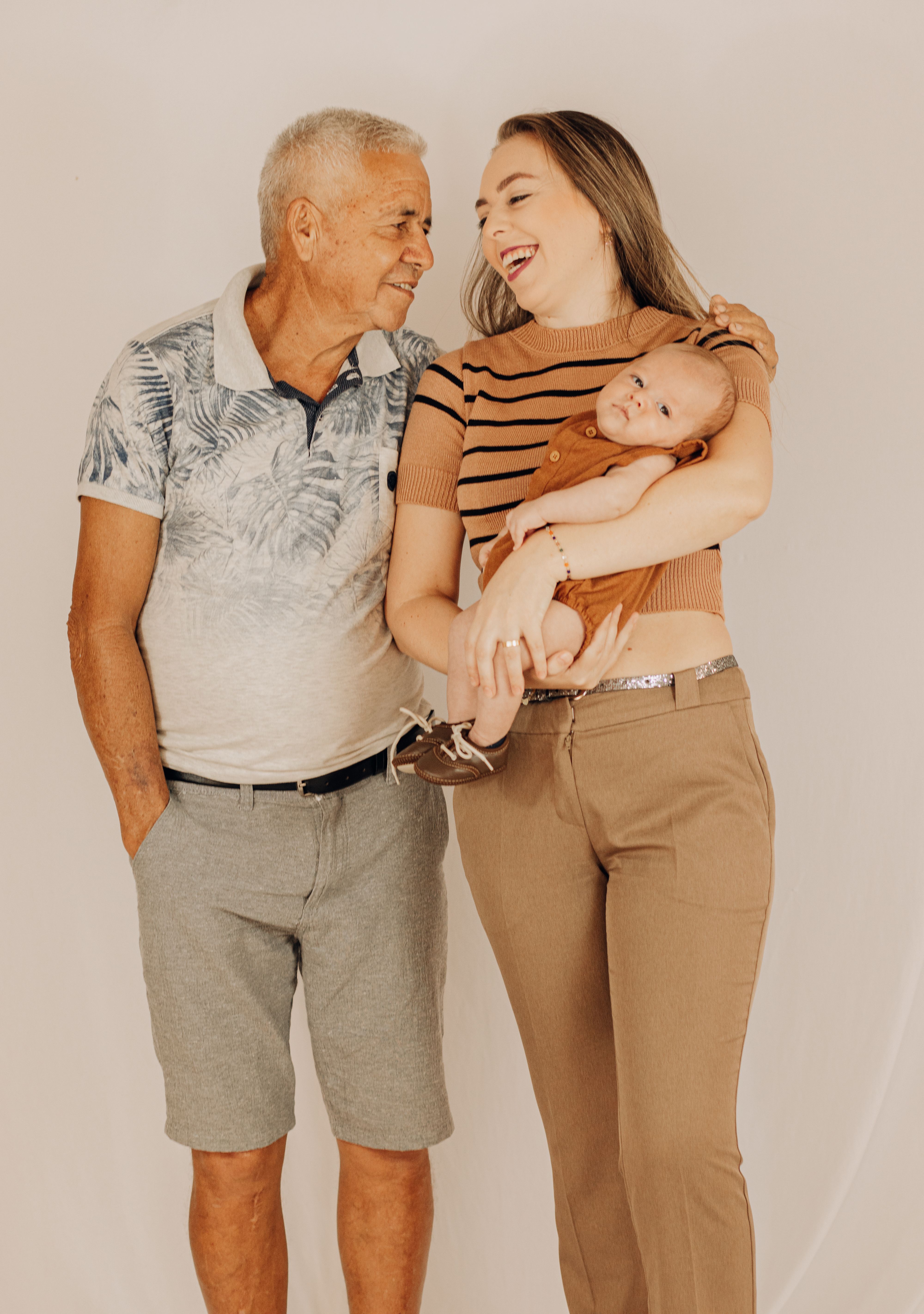 An uplifting family photo capturing love and togetherness with a grandfather, mother, and smiling baby.