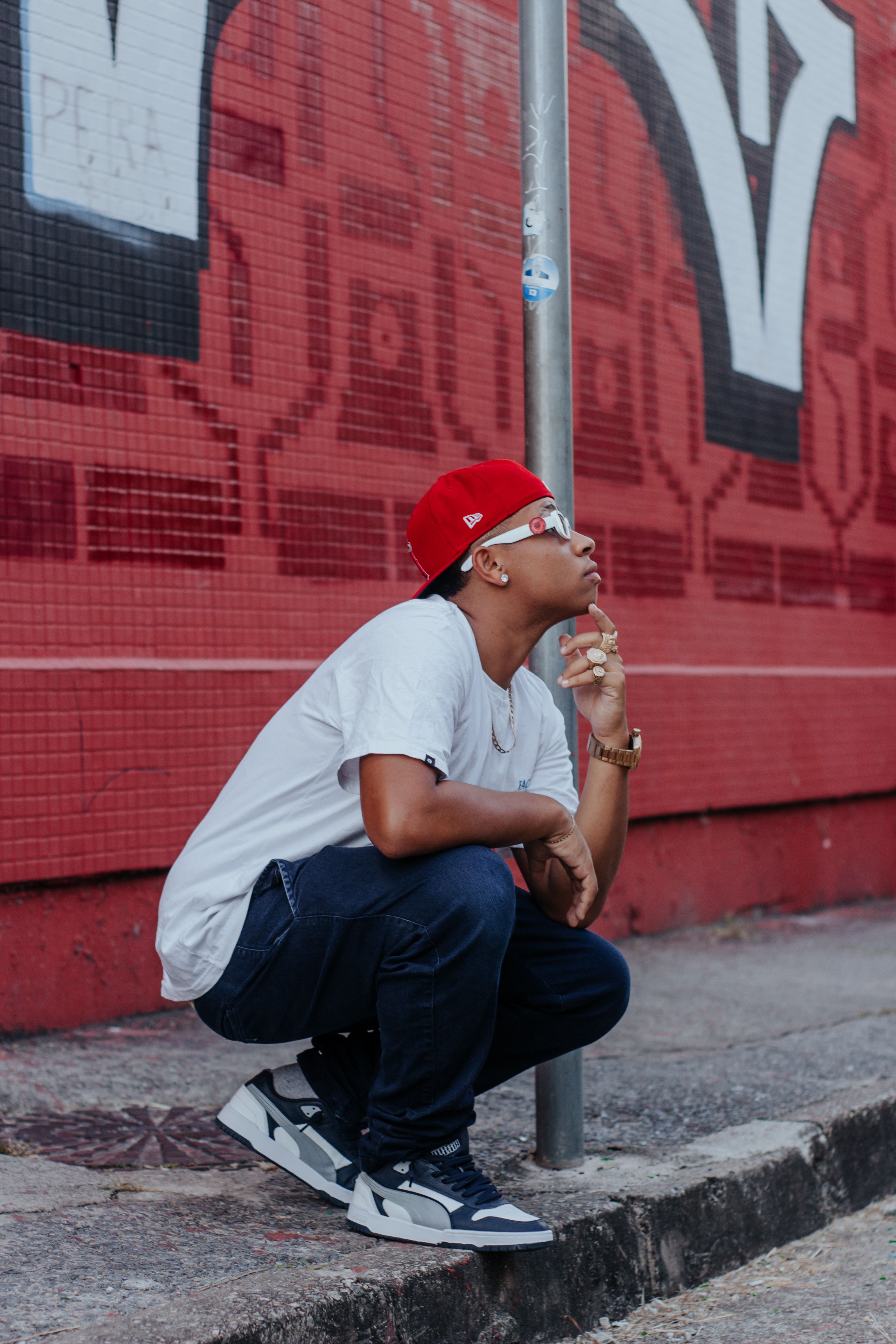 A stylish person in urban wear poses thoughtfully against a vibrant graffiti backdrop.