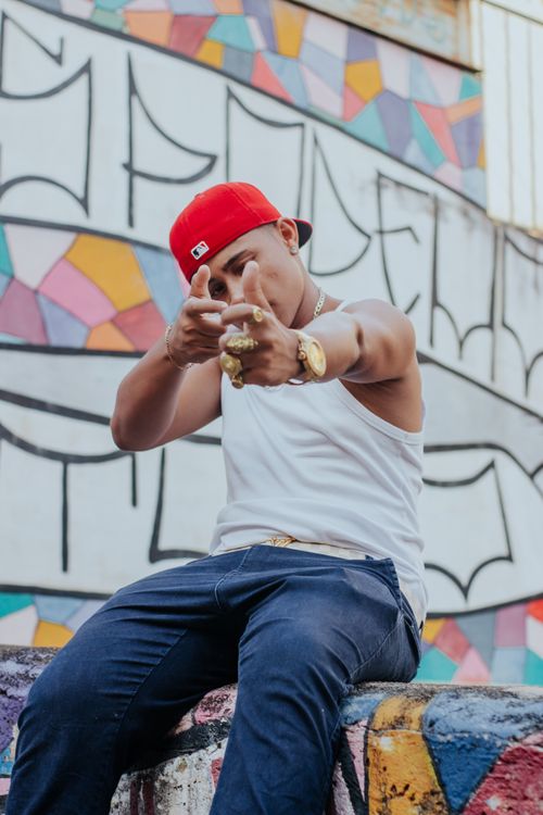 Free A stylish man in a red cap poses against a vibrant graffiti wall, showcasing urban fashion. Stock Photo