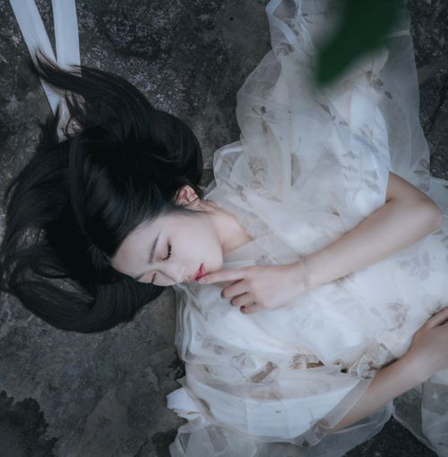 Free Elegant portrait of a woman lying down with eyes closed, captured from above in soft lighting. Stock Photo
