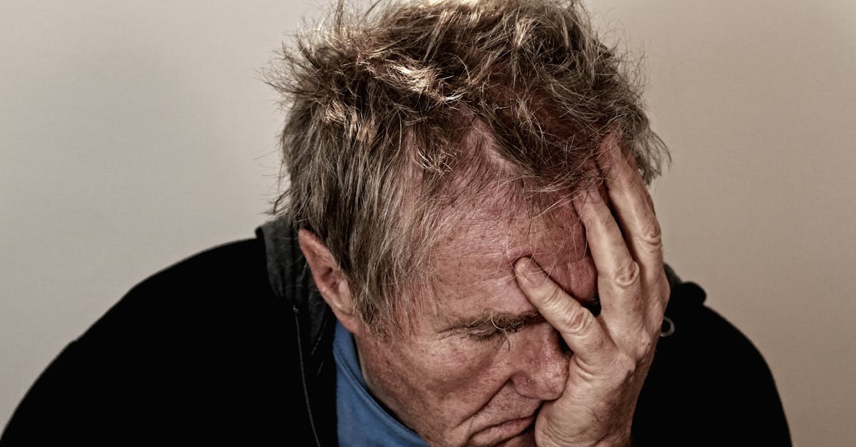 Portrait of an elderly man feeling stress and disappointment, holding his head in his hands.