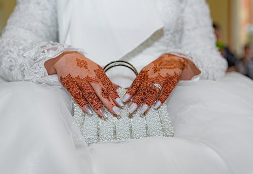 A bride with henna on her hands holding a purse