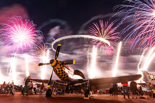 Fireworks explode over an airplane at night