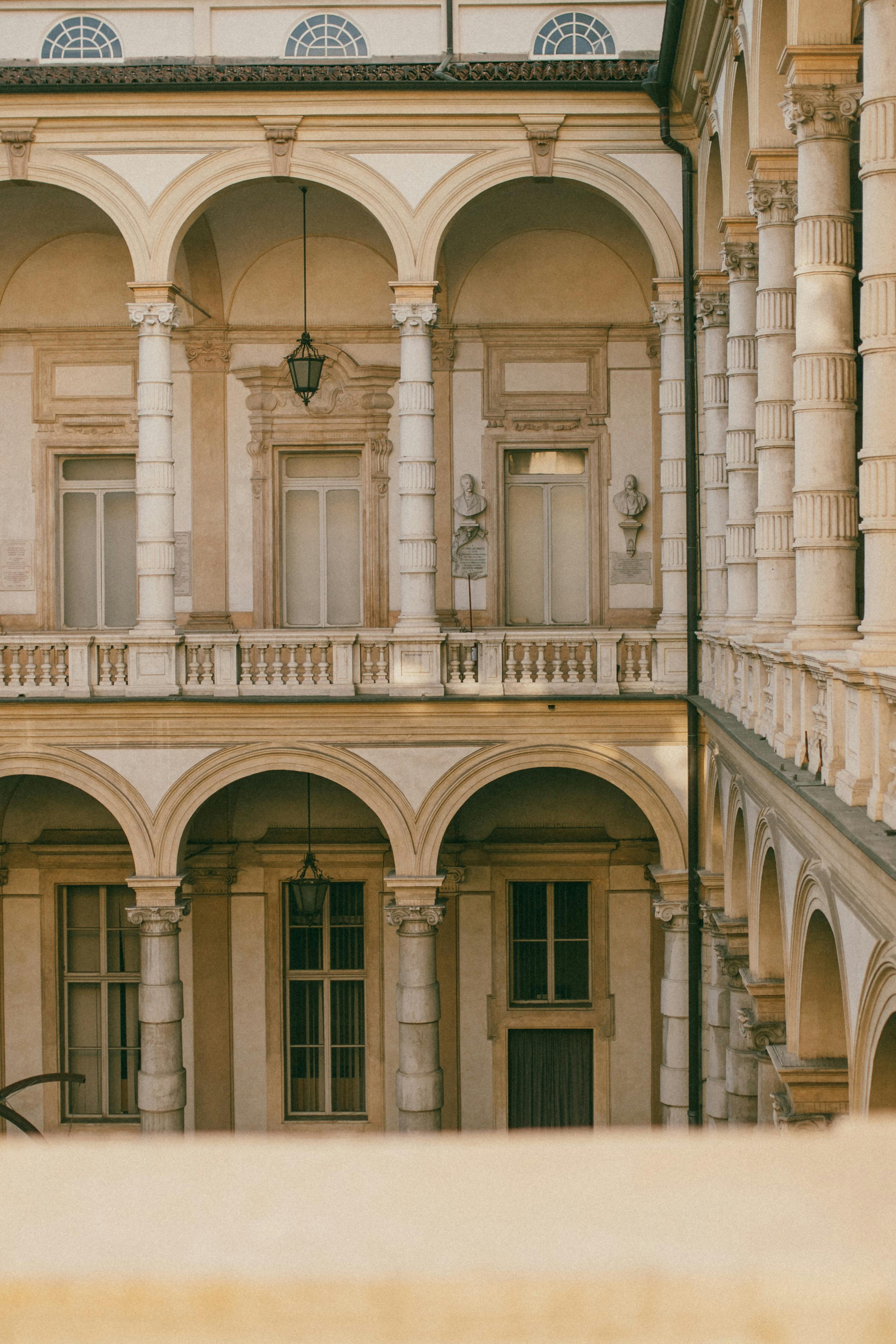 Elegant view of a historic Italian courtyard featuring arches and columns, showcasing classic architecture.