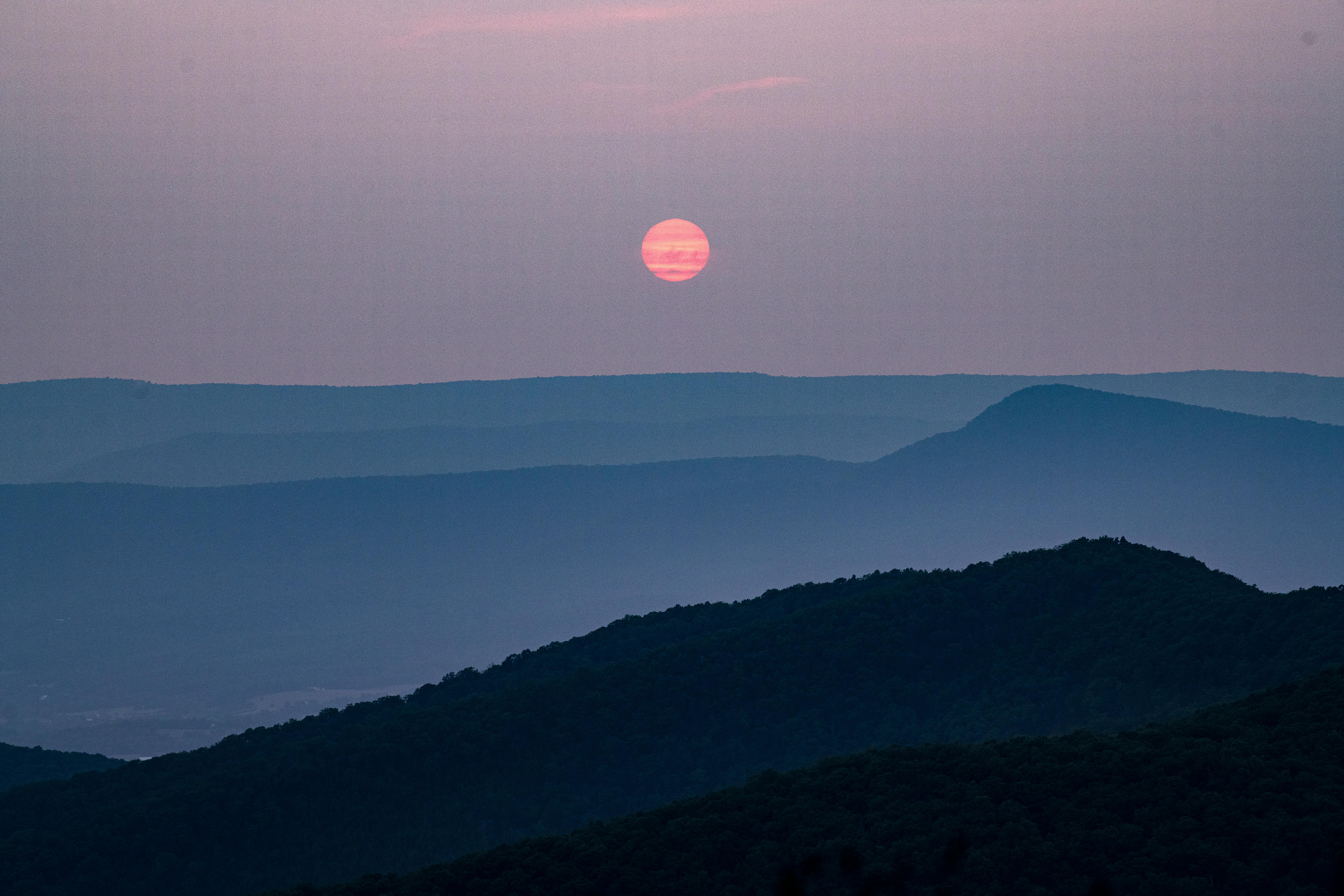 Peaceful view of sunset over layered hills. Calm and atmospheric.