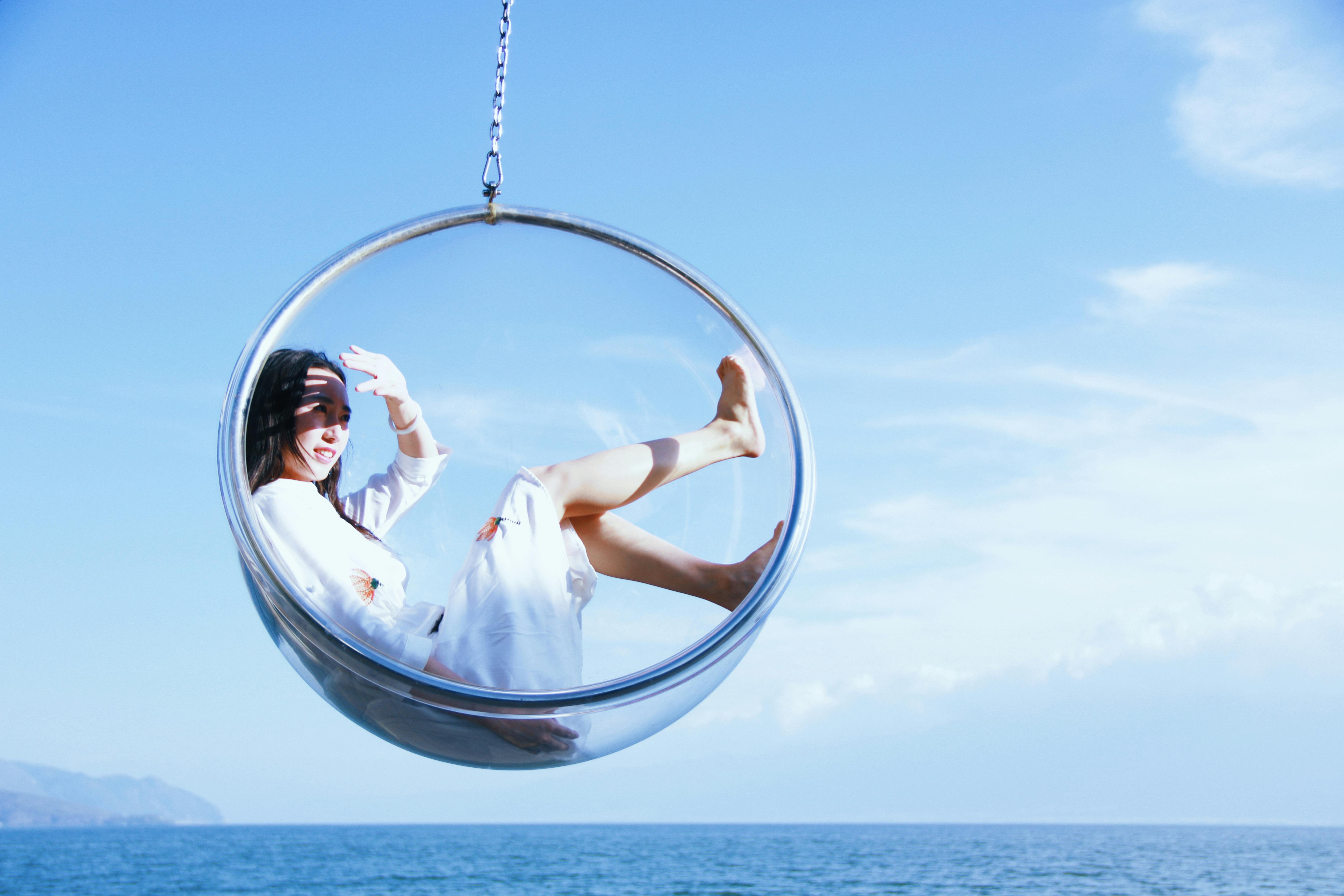 woman sitting on a glass hanging chair