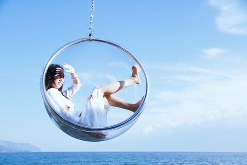 Free Woman Sitting On A Glass Hanging Chair Stock Photo