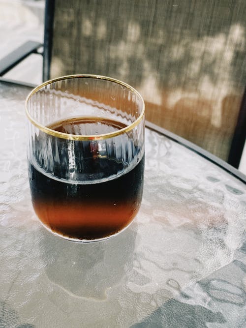 A glass of dark coffee sitting on a table