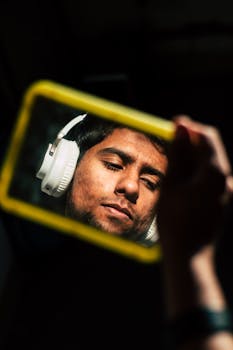 Man with headphones reflected in mirror, showcasing a calm, introspective mood.