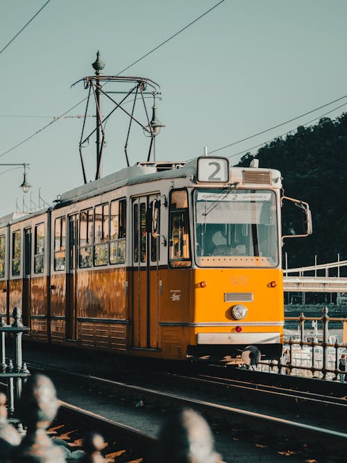 A yellow tram on the tracks next to a building