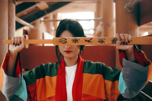 An artistic portrait of a woman holding a katana, showcasing traditional fashion and style.