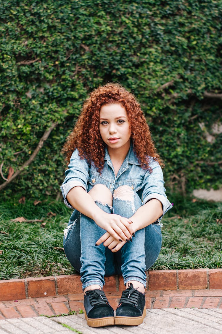 A Woman With Curly Hair Sitting Down