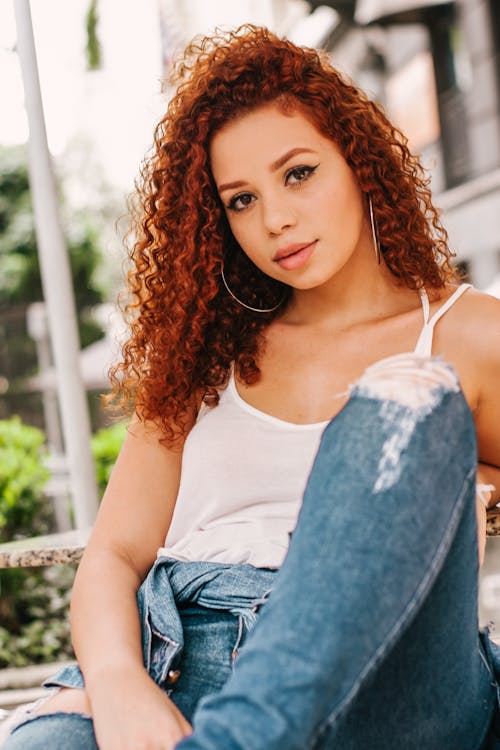 Photo of Sitting Woman in White Top and Blue Denim Jeans Posing