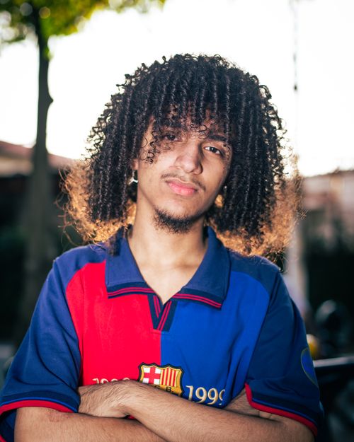 Free Young man with curly hair wearing FC Barcelona jersey in an outdoor setting. Stock Photo