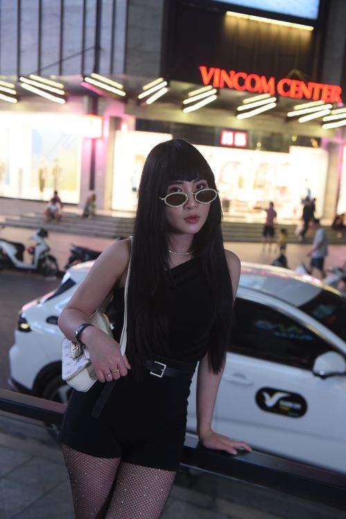 Free Stylish Asian woman in black attire poses confidently on city street at night. Stock Photo