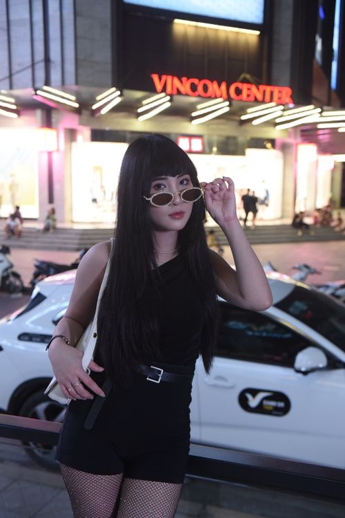 Free Fashionable woman posing at night in front of Vincom Center, showcasing urban style. Stock Photo