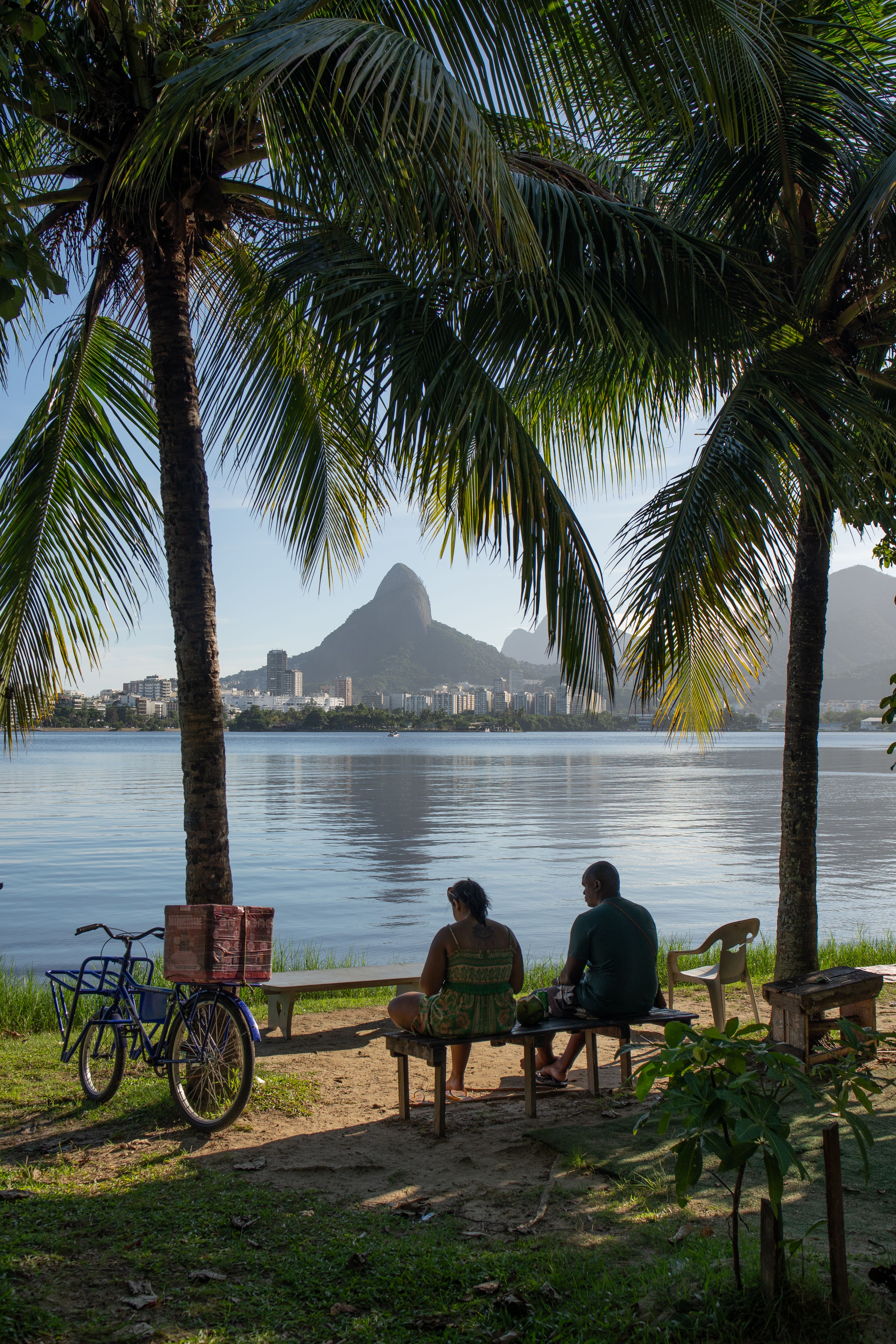 A couple sitting by the lagoon in Rio de Janeiro, enjoying the scenic view of the mountains.