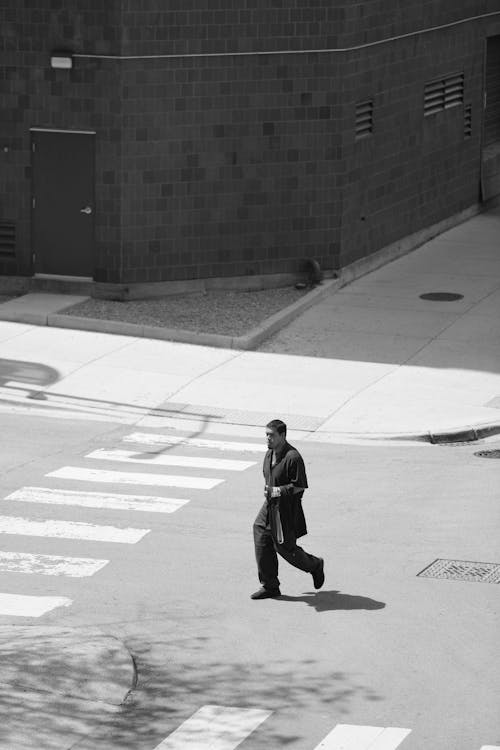 A man walking across the street in a black and white photo