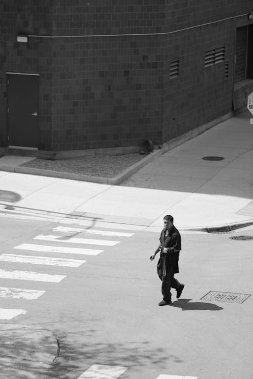 A man walking across the street in a black and white photo