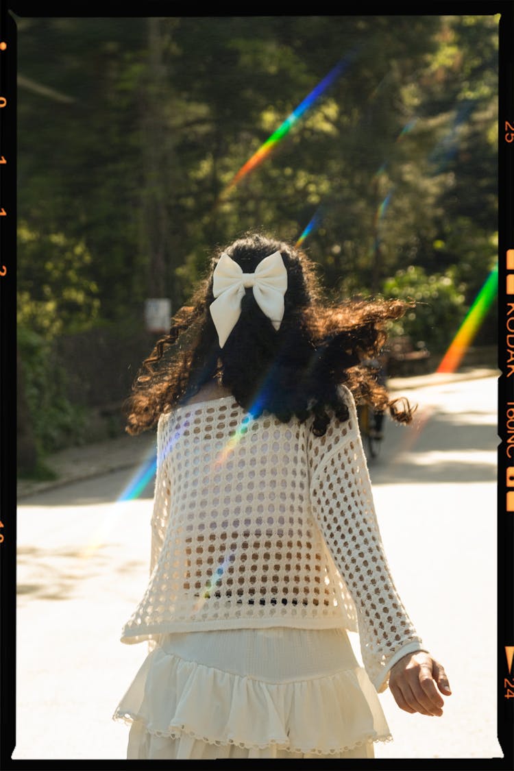 Back View Of A Girl With A Bow In Her Hair Walking In A Park 